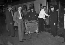 166698 Afbeelding van een kruier tijdens het inladen van de bagage in een trein (Pullman) langs het perron van het ...